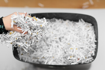 Pocięte dokumenty firmowe zniszczone w niszczarce do papieru wyrzucane do kosza na śmieci 