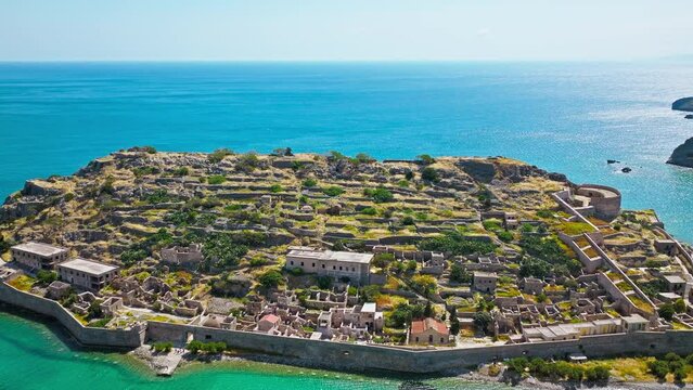 Scenic Aerial view of antique Fortress Island in Crete, Greece with tourists visiting. Spinalonga barren arid rocky islet in Elounda. Venetians built bastion-type seaward fortresses in Mediterranean