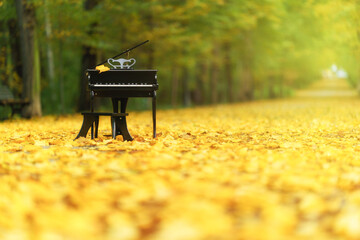 A piano standing on a path in the park in the autumn aura