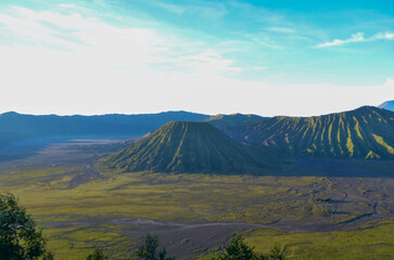 Panoramic view of a lush green volcano, its slopes gently descending into a vast, flat plain under...