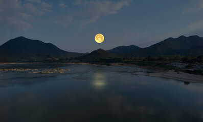 Moon rise over mountains and river in evening