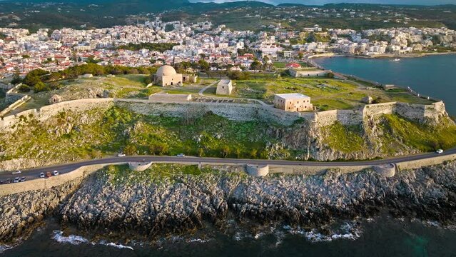 Aerial view of Venetian Fortezza Castle with luxury villas typically Greek whitewashed exterior in Crete. View from above of fortress ruins citadel offering panoramic views of Rethymno town and port.