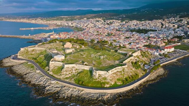 Aerial view of Venetian Fortezza Castle with luxury villas typically Greek whitewashed exterior in Crete. View from above of fortress ruins citadel offering panoramic views of Rethymno town and port.