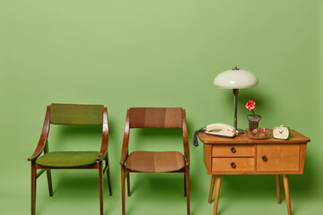 Vintage style. Horizontal shot of empty room with old chairs and table isolated over green background. Nostalgia and past time concept. Old furniture.