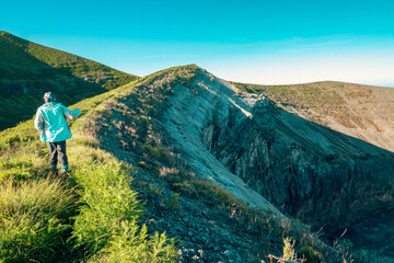 A hiker at the rim of the volcanic crater - the ash pit on Mount Ol Doinyo Lengai in Tanzania