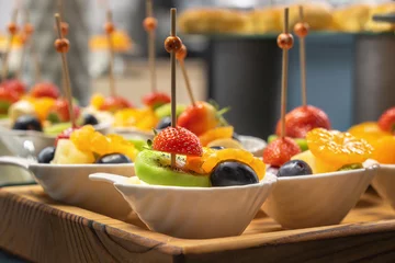 Foto op Plexiglas Fruit salad in a white bowl on a wooden tray prepared for a buffet table. Close-up © alexey_arz