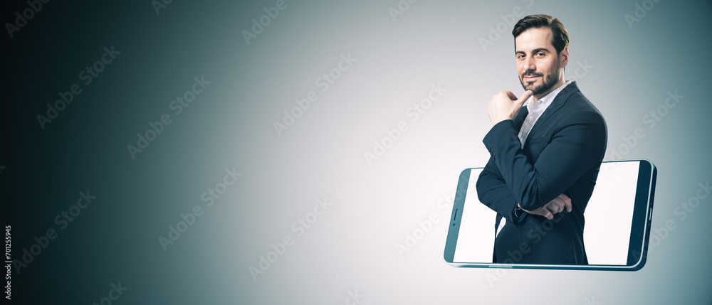 Poster cheerful young european businessman inside smartphone on gray background with mock up place for your