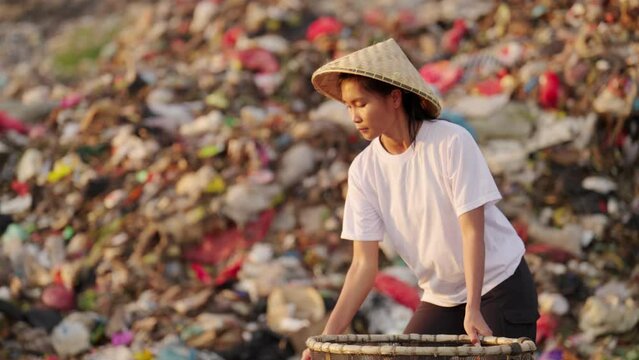 Asian woman scavenging or waste picking in landfill in asia, pollution