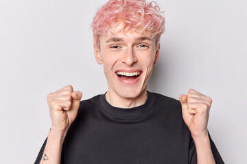 People and happiness. Indoor photo of young glad smiling broadly European male with pink hair standing in centre isolated on white background excited as if got or did something desirable or important
