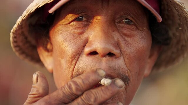Close-up portrait of senior southeast asian male smoker smoking cigarette