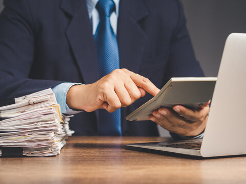 Businessman uses a calculator to calculate the cost of goods sold and profit from a product or service while sitting at a desk