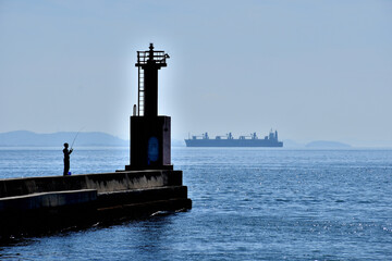 灯台のある風景、釣り人とタンカー。