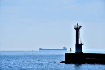 灯台のある風景、釣り人とタンカー