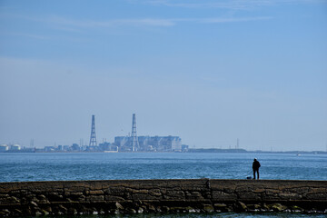火力発電所の対岸で釣りをする人。