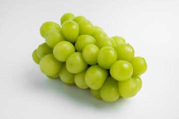 A single Shine Muscat grape with water droplets on a white background