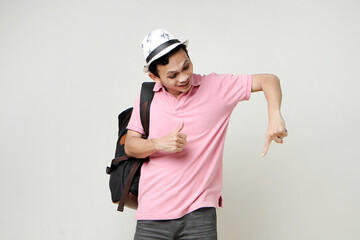 Asian man backpacker ponting finger and give thumb up gesture. digital nomad and travelling concept. on isolated background