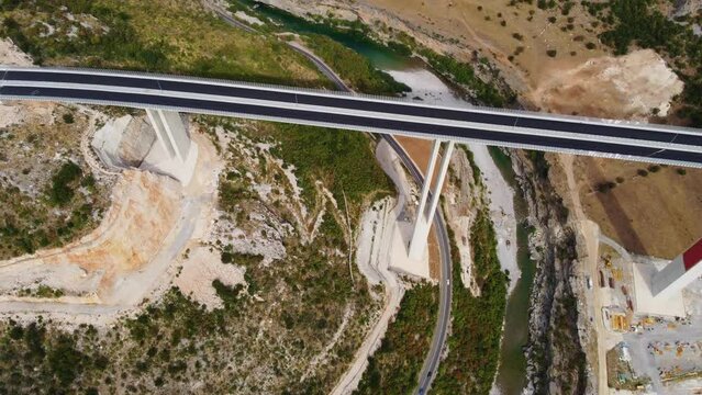 Top drone view of new modern expensive highway asphalt two lane road bridge over the Moraca river canyon in Montenegro, Europe. Motorway of reinforced concrete bridge in picturesque mountain valley.