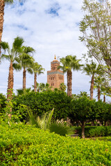Photo of the tower of the Koutoubia mosque seen from the gardens next to the mosque. Cloudy day.