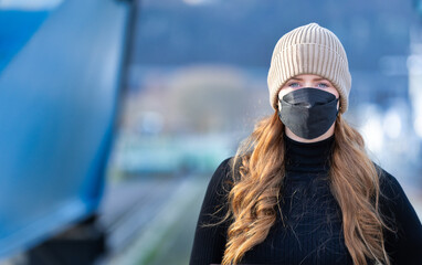Woman with red long hair, blue eyes, young with FFP2 mask, wearing beige cap and black sweater,...