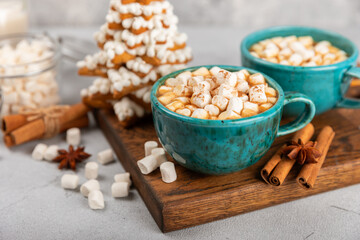 Hot drink with marshmallows and candy cane in cup on texture table.Cozy seasonal holidays.Hot cocoa with gingerbread Christmas cookies.Hot chocolate with marshmallow and spices.Copy space.
