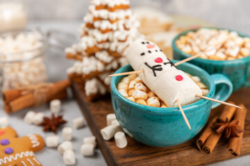 Hot drink with marshmallows and candy cane in cup on texture table.Cozy seasonal holidays.Hot cocoa...