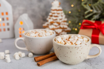Hot drink with marshmallows and candy cane in cup on texture table.Cozy seasonal holidays.Hot cocoa with gingerbread Christmas cookies.Hot chocolate with marshmallow and spices.Copy space.