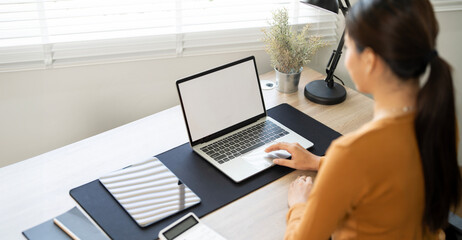 Rear view of young woman using laptop computer at home, mockup blank screen laptop.