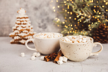 Hot drink with marshmallows and candy cane in cup on texture table.Cozy seasonal holidays.Hot cocoa with gingerbread Christmas cookies.Hot chocolate with marshmallow and spices.Copy space.
