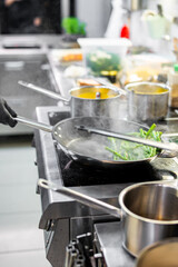 Professional chef cooking asparagus in frying pan on stove in restaurant kitchen