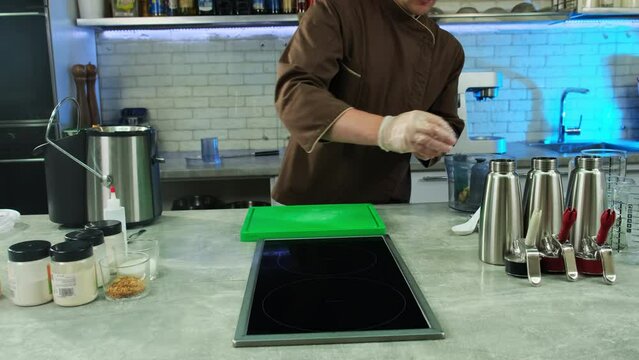 Culinarian donned in gloves methodically wipes kitchen equipment using rag. Contribution to aesthetic charm of cooking scenes