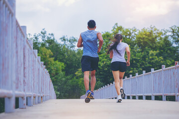 Young couple running together on road across the bridge. Couple, fit runners fitness runners during outdoor workout.