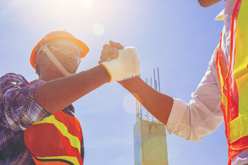 Architect and engineer construction workers shaking hands while working at outdoors construction...