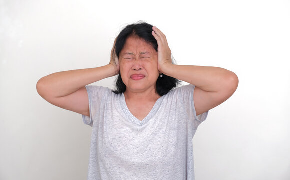 A woman closing her eyes tightly while covering her ears with her hands