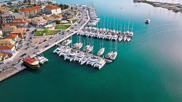 Aerial view of D-Marin Lefkas Marina full of boats and ships in Lefkada. The island's capital and port town with turquoise waters, Greek-style houses with colourful shutters, and wooden balconies.