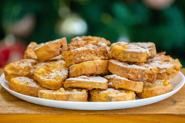 Typical Brazilian Christmas Rabanadas with egg yolk cream and cinnamon, Spanish Torrijas on golden plate on a Christmas dinner table. Fine details