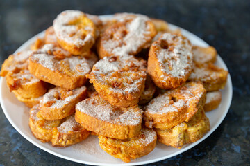 Typical Brazilian Christmas Rabanadas with egg yolk cream and cinnamon, Spanish Torrijas on golden plate on a Christmas dinner table. Fine details