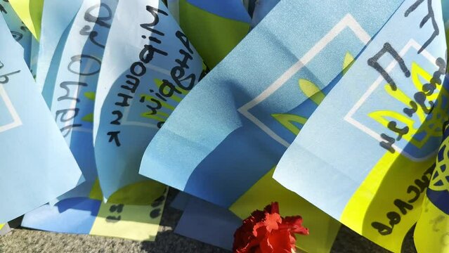 Many small flags of Ukraine with names of the dead war against russia. Memorial of the fallen soldiers, children, women in the center of Kyiv. Concept of tragedy and misfortune. Closeup