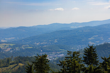 Beautiful green and blue panorama of layers of mountains and trees and some fields seen from top of viewing tower at highest mountain in this area