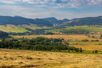 Fototapeta premium Beautiful landscape of glades and clearing full of fields and trees between it at mountains at sunny cloudy day
