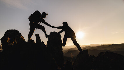 silhouette of Teamwork of three  hiker helping each other on top of mountain climbing team. Teamwork friendship hiking help each other trust assistance silhouette in mountains, sunrise.