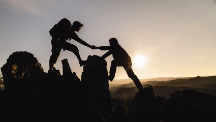 Poster silhouette of Teamwork of three  hiker helping each other on top of mountain climbing team. Teamwork friendship hiking help each other trust assistance silhouette in mountains, sunrise. © Tinnakorn