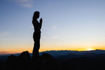 Silhouette of The girl  prayed  in the mountains to think of a loving God, we praise God. - obrazy, fototapety, plakaty