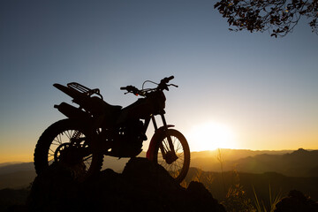 motocross bike against beautiful lights, silhouette of a  motocross motorcycle On top of rock high...