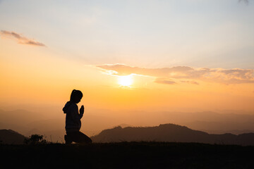  Silhouette of Woman praying for thank god praying with her hands together to think of a loving...