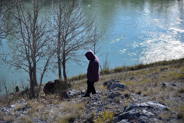 A woman walks along the river in autumn.