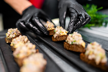 Professional chef cooking forshmak of herring with black bread in restaurant kitchen