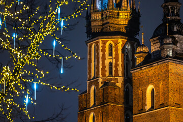 The tower of St. Mary's Basilica in Krakow against the background of Christmas decorated trees....