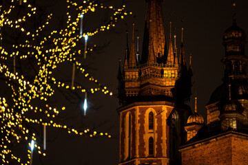 The tower of St. Mary's Basilica in Krakow against the background of Christmas decorated trees....