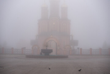 Cityscape. City street during fog. In the background is a religious building and a non-working...