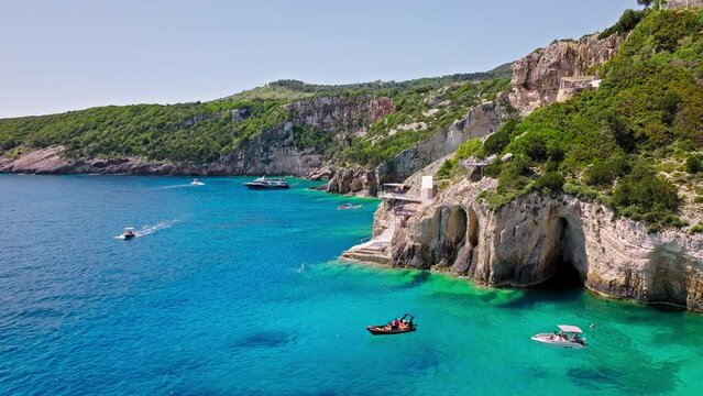Aerial view of tourists on vacation on a cruise ship at Blue Natural Caves and arches in Zakynthos, Greece. Turquoise transparent blue water, Tourist attraction accessible by boats on Greek Islands.
